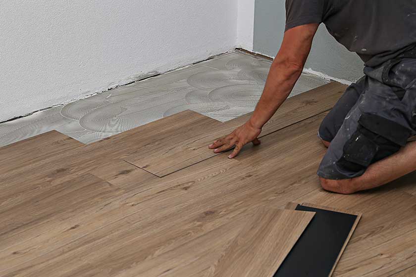 The worker installing new vinyl tile floor